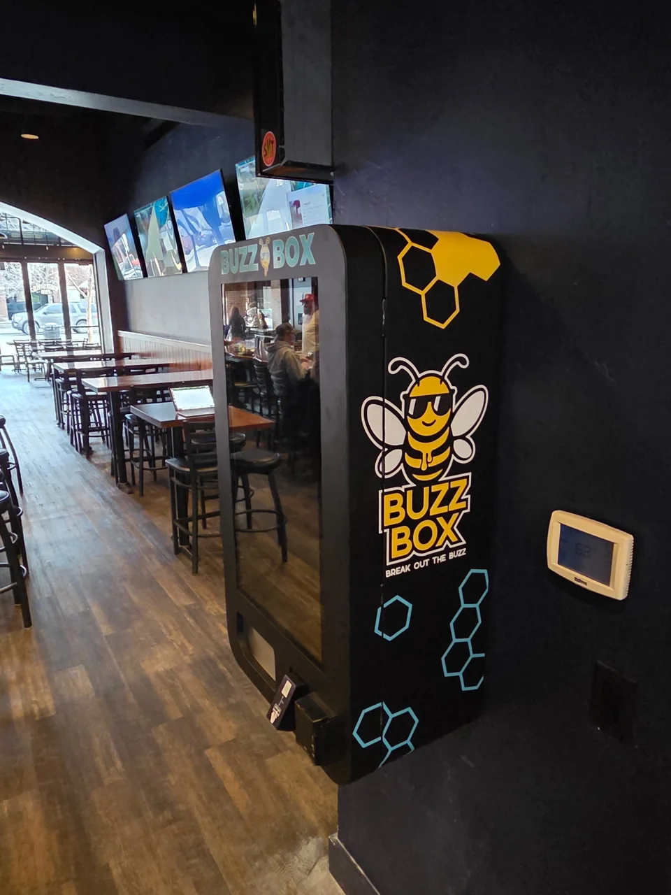 Buzz Box machine with gold mascot artwork beside the seating area at Cousins Pub